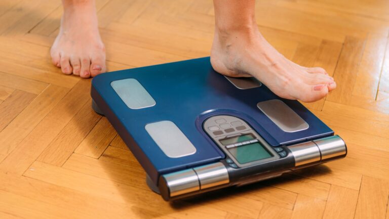 A woman's foot stepping onto a scale. Image to demonstrate the way we see body fat.