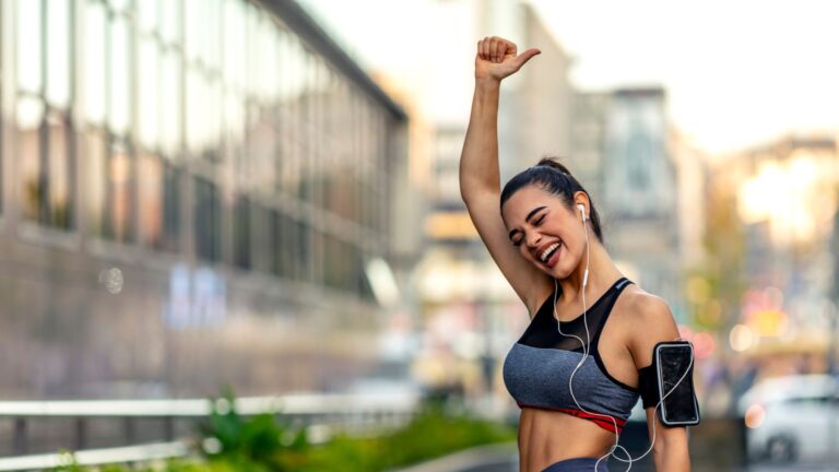 A woman pumps her fist in the air, sweaty and red-faced after a run. Image demonstrates natural ways to boost your energy.