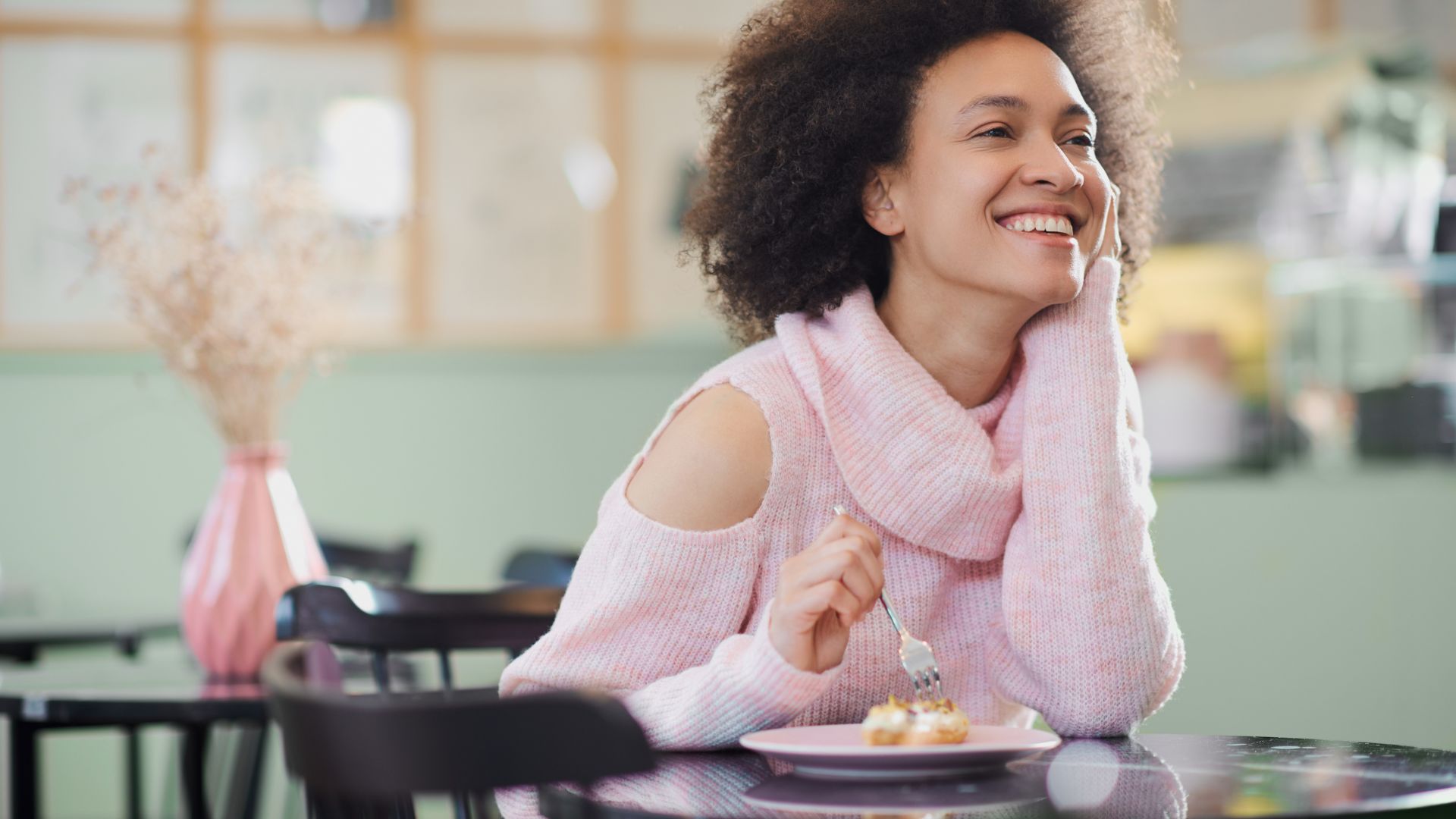 A woman smiles into the distance while spearing a piece of her dessert with a fork. Image to demonstrate you can lose weight while eating dessert.