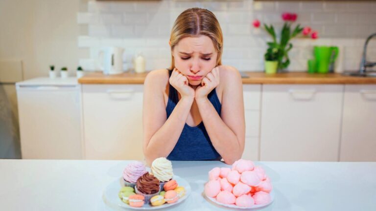 A woman in her kitchen staring at desserts she can't have because of her no sugar diet