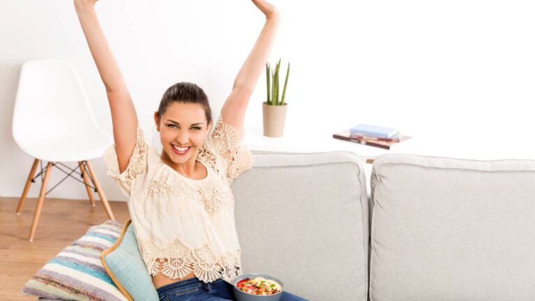 A woman sitting on a couch and celebrating the things she did to lose weight quickly and permanently.