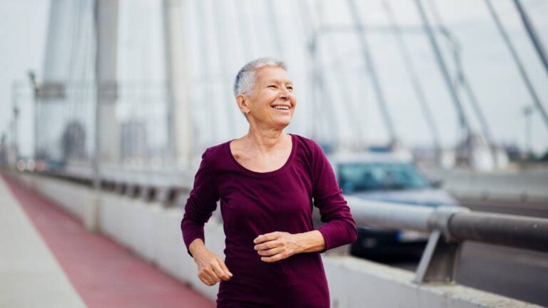 An older woman jogging on a bridge as a better way to weight loss over calorie deficit diets.