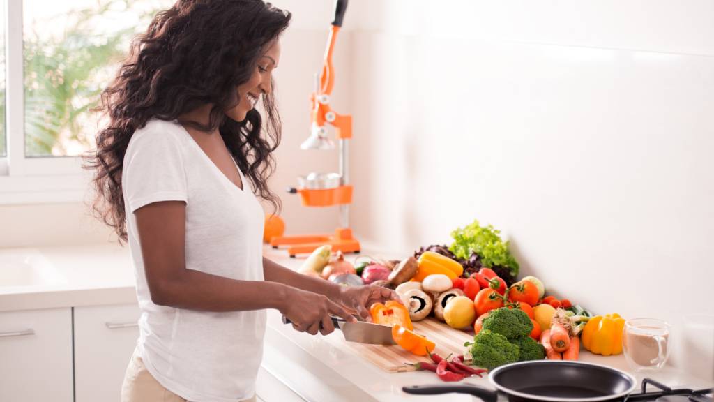 A women preparing healthy food in her kitchen while she thinks about what causes slow metabolism.