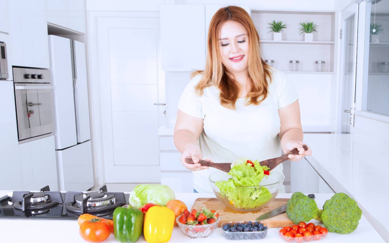 A woman in her kitchen is preparing healthy food that assists in a low sugar diet.