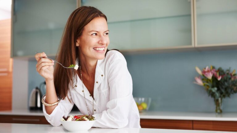 woman eating salad over counter smiling weightloss