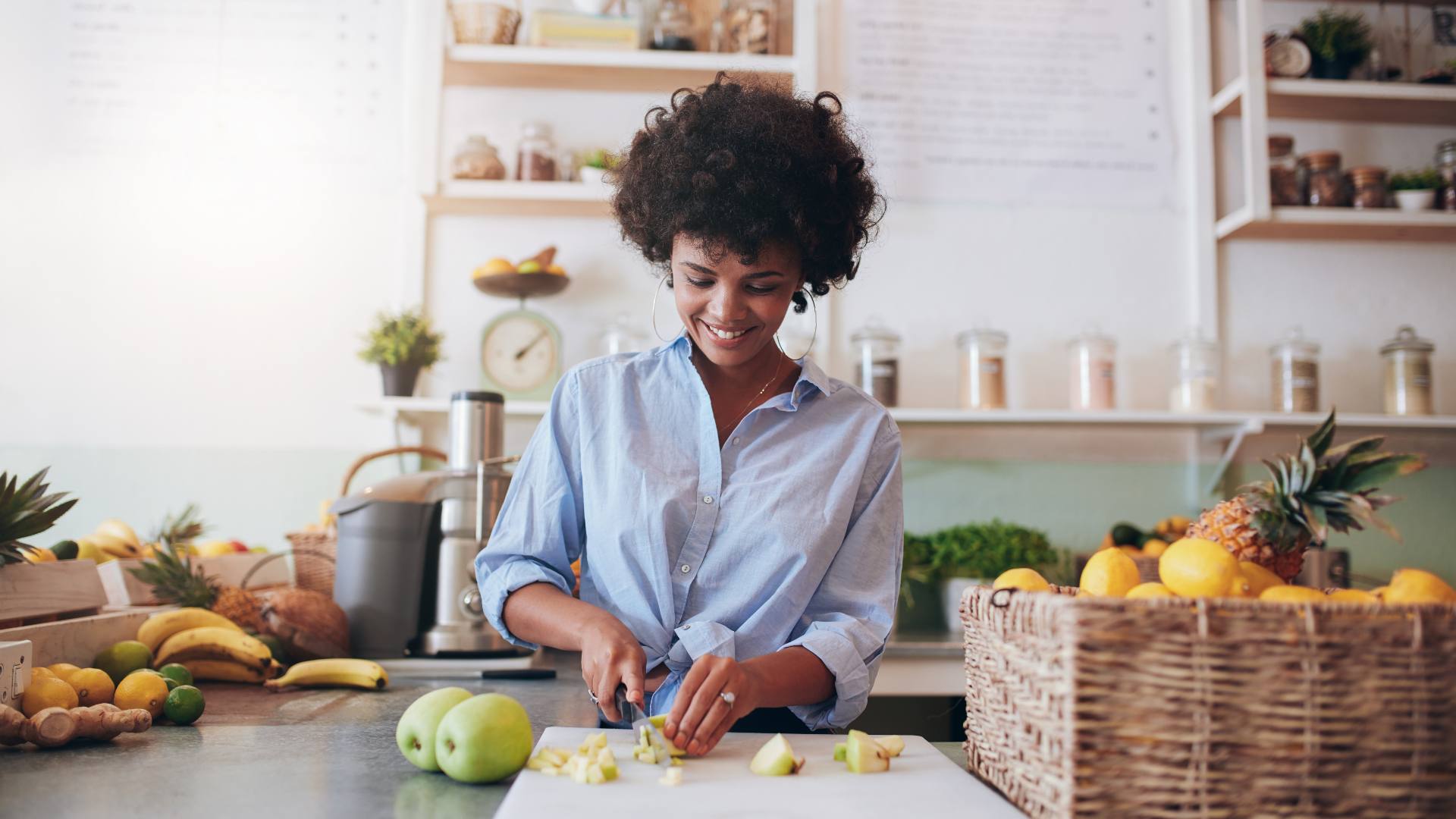 woman chopping fruits and vegetables on counter smiling