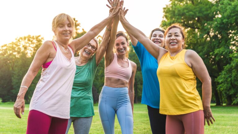 A group of women of all ages standing in a circle and high-fiving. They have successfully rebooted their metabolism and are healthy and vibrant.