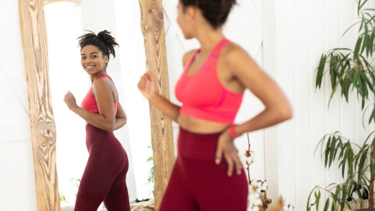 A healthy woman looking at herself in the mirror happily, as she's learned how to increase metabolism and lose weight.