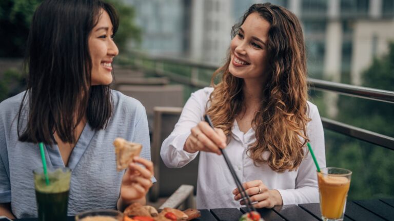 Women eating at a table and smiling, showing that there's a difference between calories and what you actually eat.
